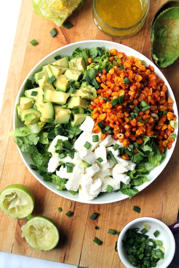 A plate of roasted corn salad with avocado and mozzarella