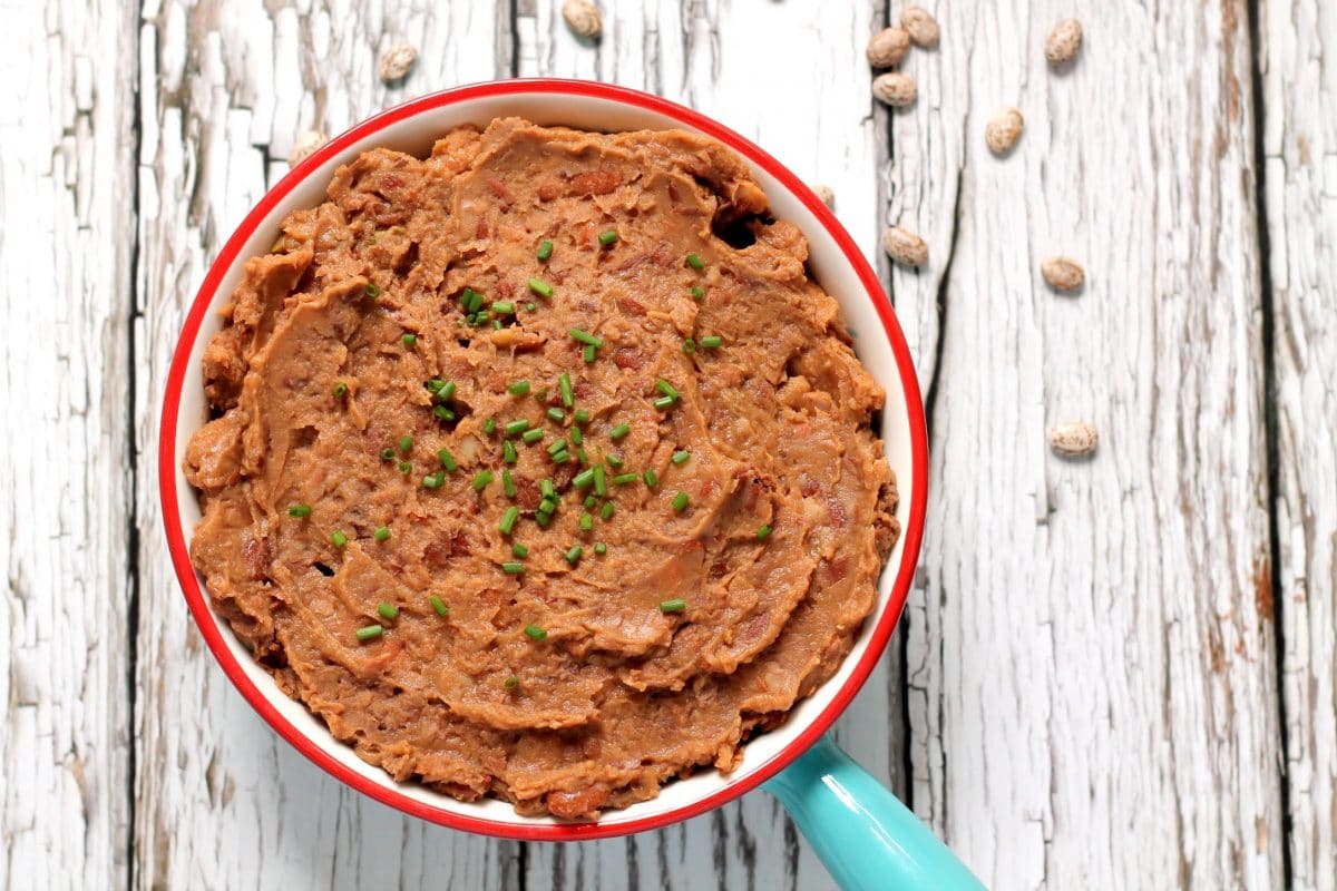 These flavor packed vegan refried beans are made in the slow cooker and have a delicious smoky edge to them! Cooking dried pinto beans in the slow cooker is an economical way to fill your freezer with tasty refried beans for quick and easy weeknight meals.