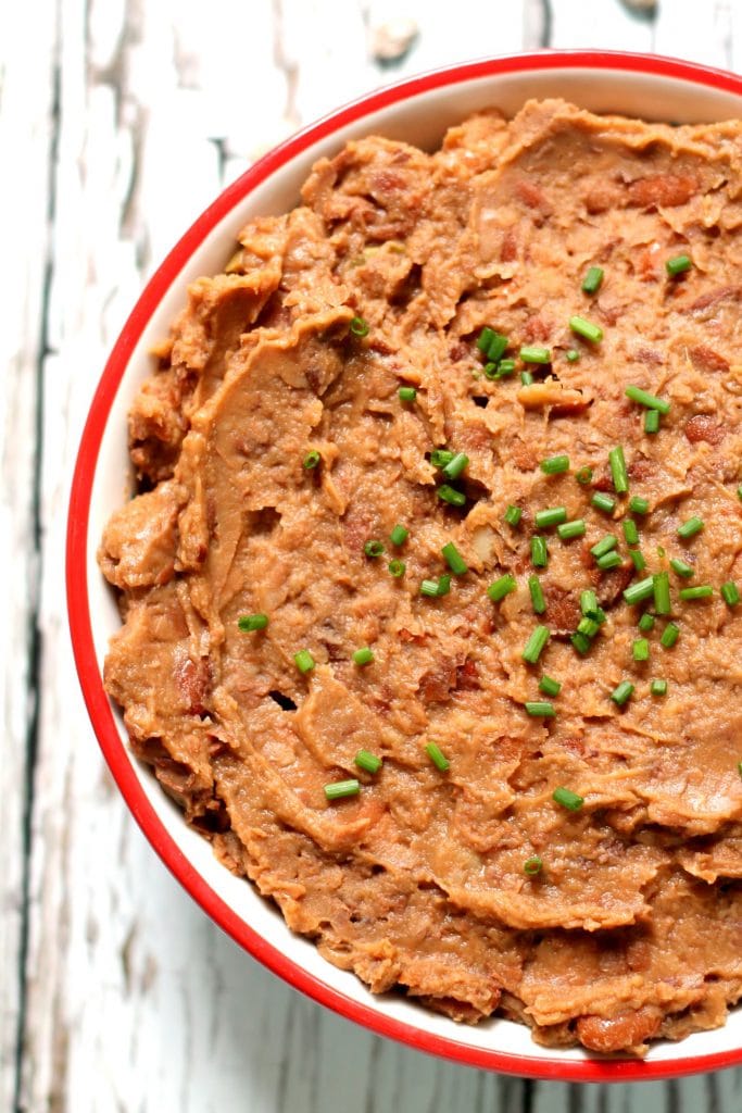 These flavor packed vegan refried beans are made in the slow cooker and have a delicious smoky edge to them! Cooking dried pinto beans in the slow cooker is an economical way to fill your freezer with tasty refried beans for quick and easy weeknight meals.