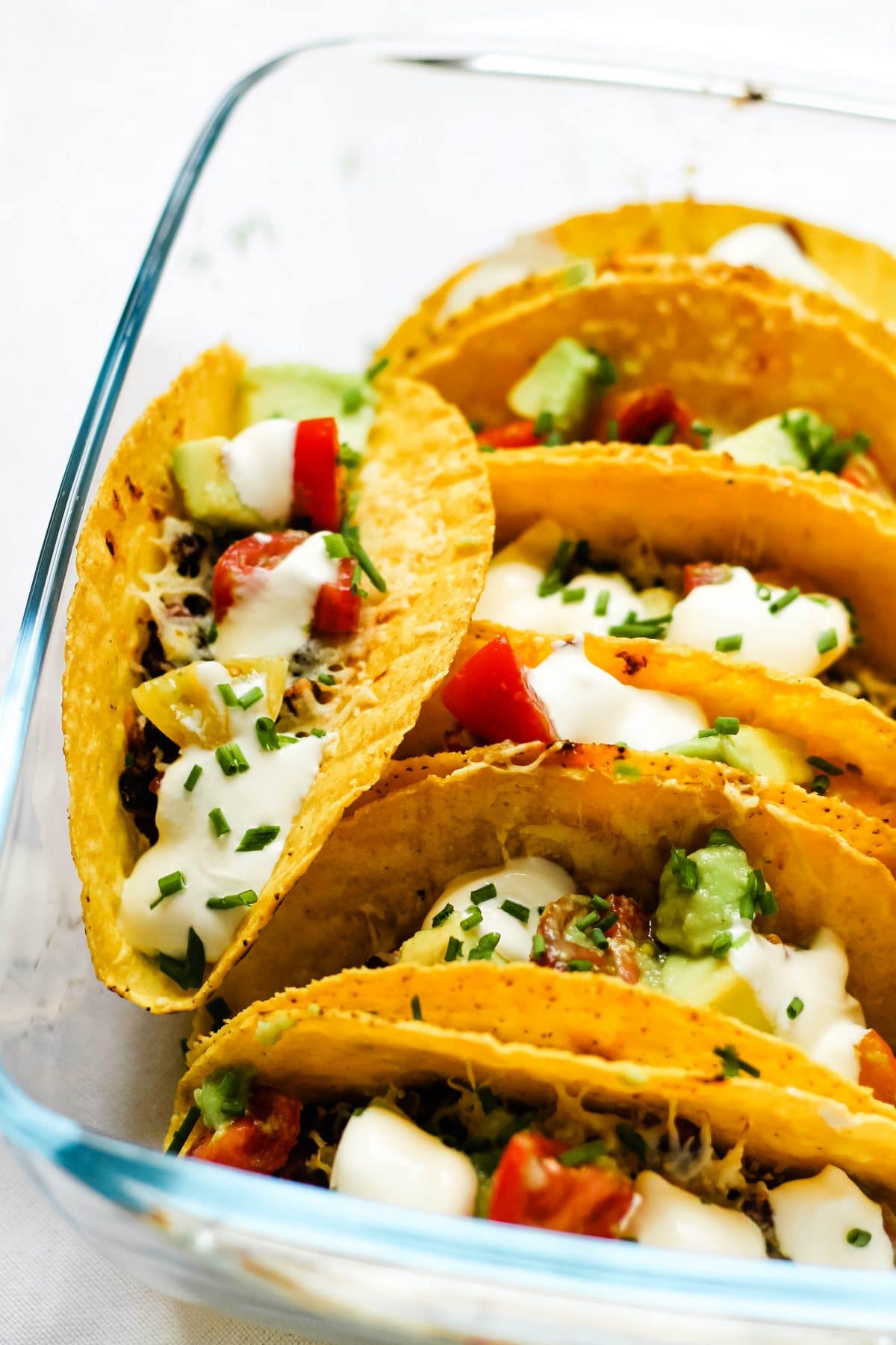 A simple 20 minute vegetarian taco dinner with black beans, smoked cheese and a fresh cherry tomato avocado salsa topping. Oven baked tacos are such a simple dinner, giving you extra crispy shells, melted cheese and a smoother workflow. Using smoked cheddar is an easy way to take classic bean and cheese tacos to the next level, making them completely irresistible! #tacos #vegetarianrecipes #easydinners #meatlessmonday