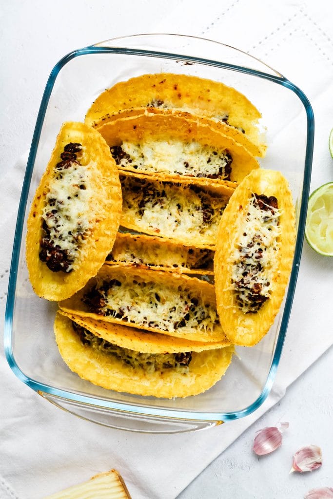 A pan of baked tacos fresh from the oven, with a bean and cheese filling.