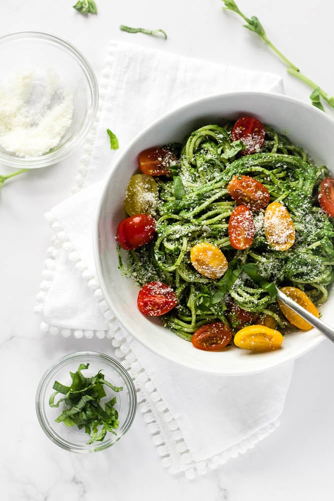 A bowl of spinach spaghetti sauce with cherry tomatoes.