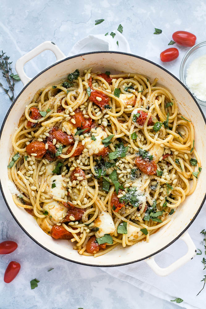 A pan of bucatini pasta with cherry tomatoes, scamorza cheese and pine nuts.