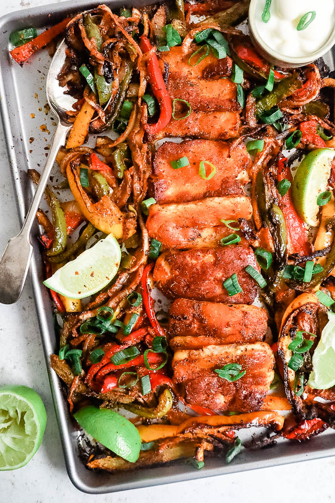 A top down view of a sheetpan with cooked roasted halloumi fajitas