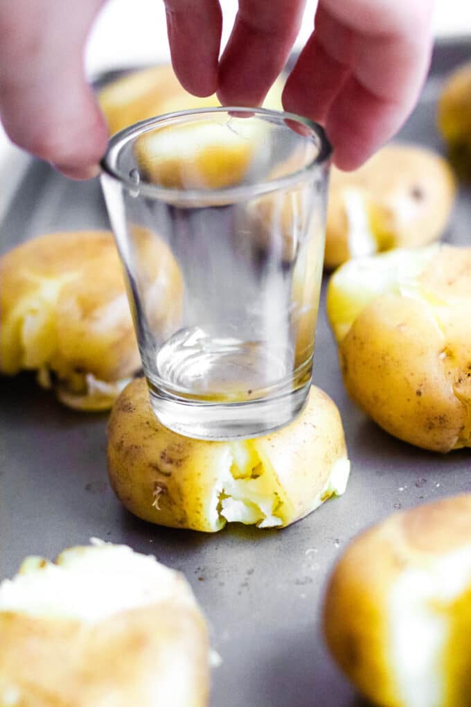Potatoes being smushed by a glass (part of the process for making smashed potatoes)