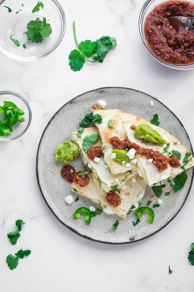 Top down view of a plate of quesadillas and toppings