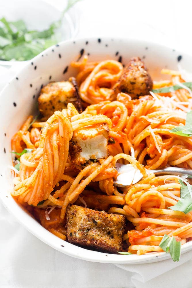 Close up shot of the bowl of spaghetti with the breaded halloumi on the fork