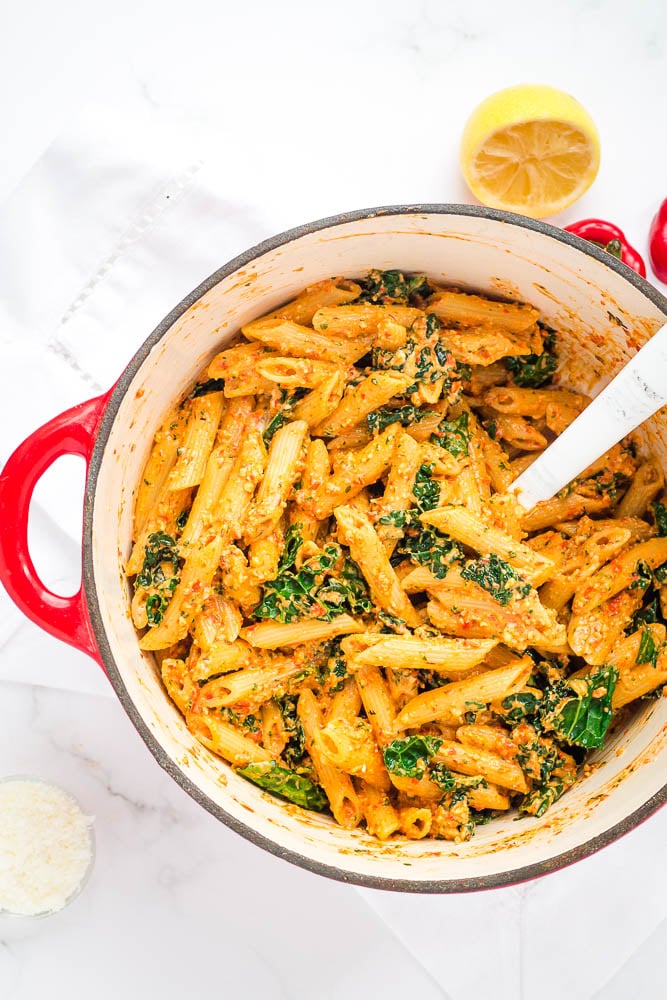 Red pepper pesto pasta in the dish, with kale mixed in
