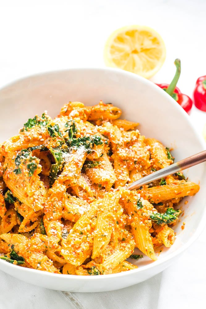 Bowl of red pepper pesto pasta with extra cheese on top