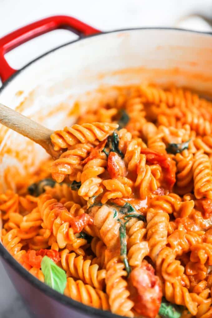 A pot of tomato mascarpone pasta with a spoon lifting some up