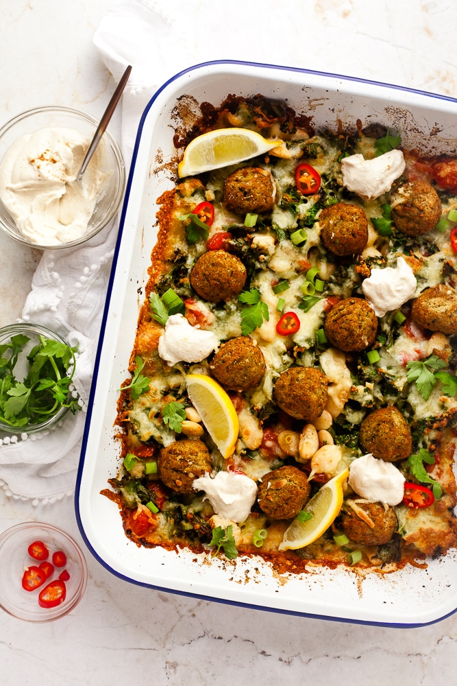 Falafel dinner bake in it's pan, with toppings next to it