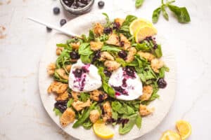 A plate of burrata salad with blueberry sauce